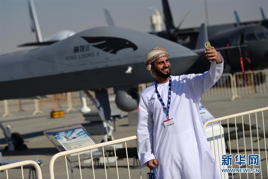 11月13日，在阿联酋迪拜航展上，一名参观者在“翼龙”无人机全尺寸模型前自拍。第15届迪拜国际航空展于12日至16日在阿联酋迪拜阿勒马克图姆机场举行。中国航空工业集团等中国企业携无人机、运输机、直升机、战斗机等产品参加展览。中国空军八一飞行表演队也首次受邀参加飞行表演。新华社记者 赵丁喆 摄 